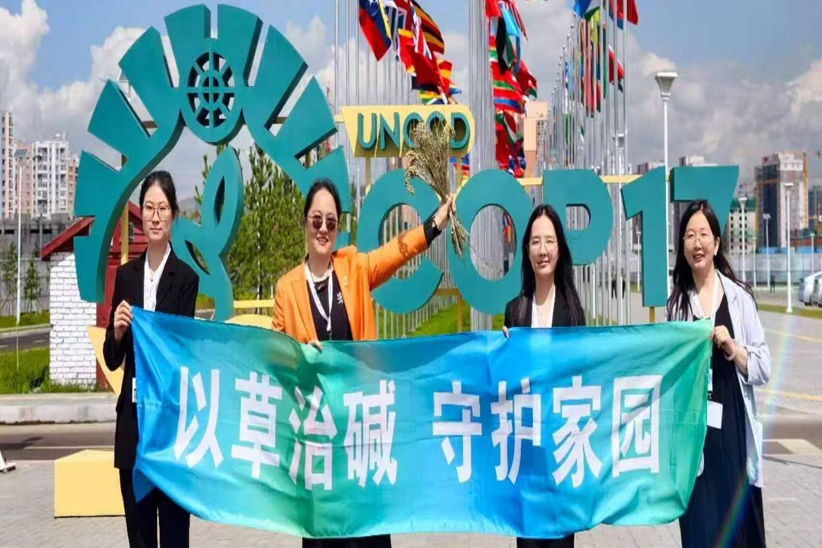 茭仙草团队在UNCCD COP17 乌兰巴托大会现场举「以草治碱守护家园」横幅合影